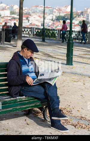 Jardim de São Pedro de Alcântara, Lissabon, Portugal: ein Mann sitzt auf einer Parkbank die Zeitung zu lesen Stockfoto