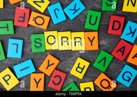 Es tut uns leid schrieb mit bunten Spielzeug Buchstaben auf dunklem Hintergrund Stockfoto