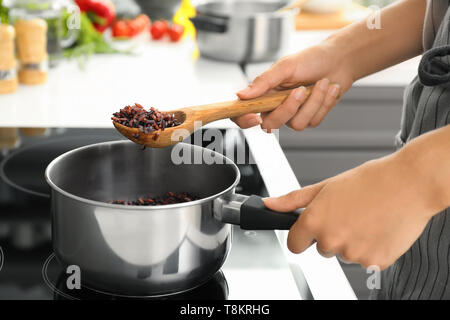 Kochen Frau Reis im Topf auf Herd Stockfoto
