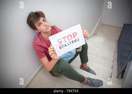 Teenage boy Holding Blatt Papier mit Text STOP Mobbing in der Schule Stockfoto