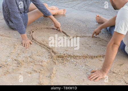 Nette junge Paare in der Nähe von Herz am Strand Sand gezeichnet Stockfoto