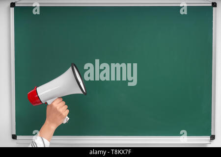 Hand der Frau mit Megaphon gegen Schiefertafel Stockfoto
