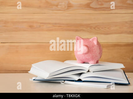 Cute Sparschwein mit Büchern auf hellem Holztisch Stockfoto