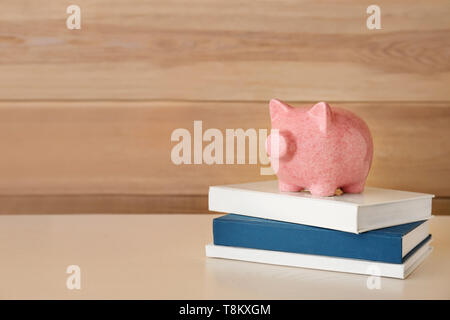 Cute Sparschwein mit Büchern auf hellem Holztisch Stockfoto