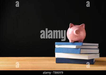 Cute Sparschwein auf der Bücher gegen den dunklen Hintergrund Stapel Stockfoto