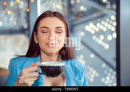 Die Liebe zum Kaffee. Portrait von süße Mädchen trinken Ihren Kaffee im Wohnzimmer in manhattam Apartment Home oder ein schickes Café genießen, trägt blaue Anzug, wh Stockfoto