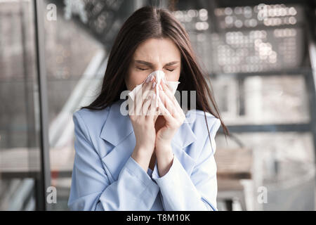 Grippe. Junge Frau Nase Allergie Grippe niesen Nase. Closeup Portrait einer schönen hispanische Mädchen tragen formalen blauen Anzug sitzen an einem Tisch auf einer c Stockfoto