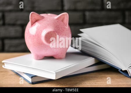 Cute Sparschwein mit Büchern auf hölzernen Tisch Stockfoto