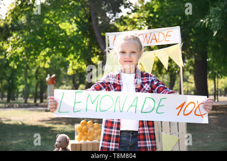 Kleines Mädchen holding Preis Banner in der Nähe von Limonade Stand in Park Stockfoto