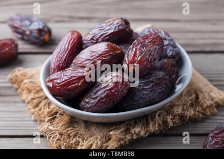 Frische Medjool Datteln in der Schüssel. Graues Holz- Hintergrund. Close Up. Stockfoto