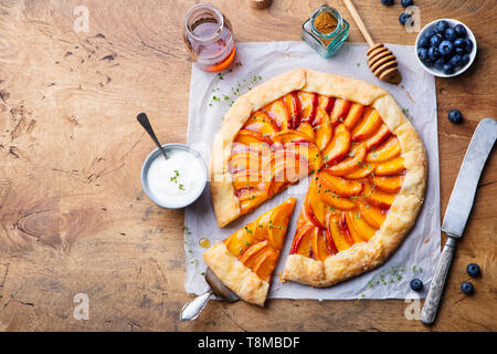 Pfirsich Galette, Torte, Kuchen mit Honig und Beeren auf einem hölzernen Hintergrund. Kopieren Sie Platz. Ansicht von oben. Stockfoto