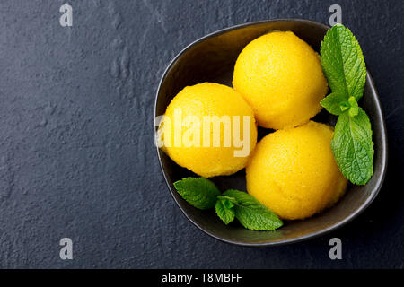 Mango Eis, Tropical Fruit Sorbet in schwarz Schüssel auf schiefer Hintergrund. Kopieren Sie Platz. Ansicht von oben. Stockfoto