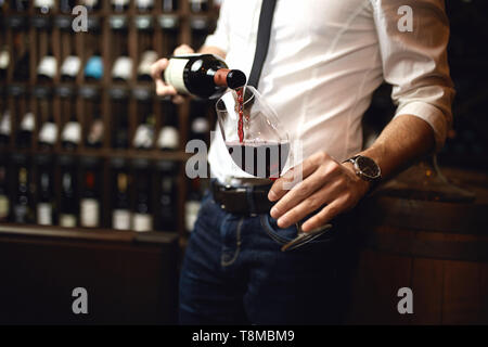 Nahaufnahme 7/8 Foto. Konzentrieren Sie sich auf die Flasche Rotwein. Reich versorgt Weinbar im Hintergrund des Fotos. Stockfoto