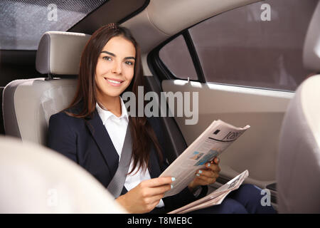 Junge Geschäftsfrau lesen Zeitung im Auto. Stockfoto