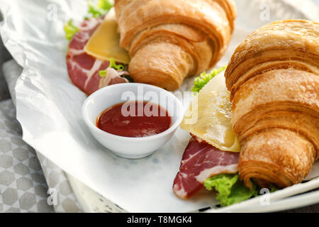 Leckere croissant Sandwiches mit Soße auf Fach, Nahaufnahme Stockfoto