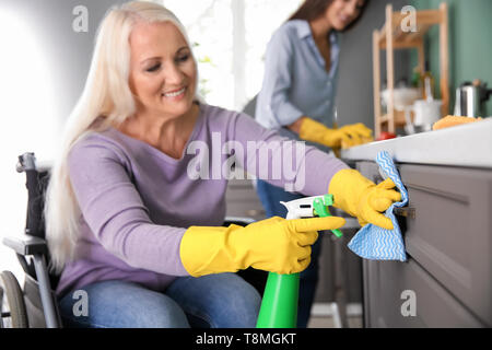 Reife Frau im Rollstuhl Reinigung Küche Stockfoto