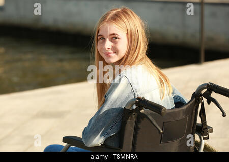 Teenage Mädchen im Rollstuhl in der Nähe des Flusses Stockfoto