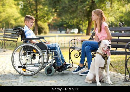 Behinderte Junge mit seiner Schwester und seinem Hund in Park Stockfoto
