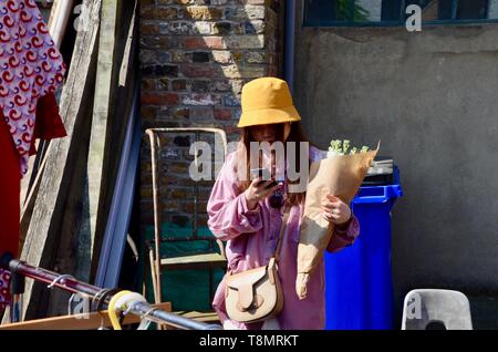 Japanische Touristen mit Blumen auf Ihr Telefon Columbia Road London suchen Stockfoto
