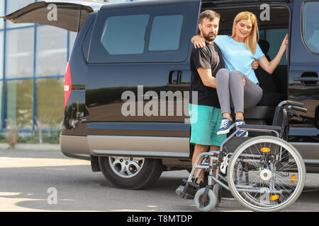 Mann helfen behinderten Frau im Rollstuhl zu sitzen Stockfoto