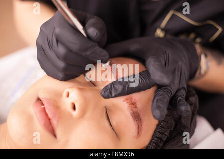 Blick von oben auf die junge Brünette in der augenbraue Tattoo Entfernung. Spezielle equipament. Frau entfernen Tattoo. Stockfoto