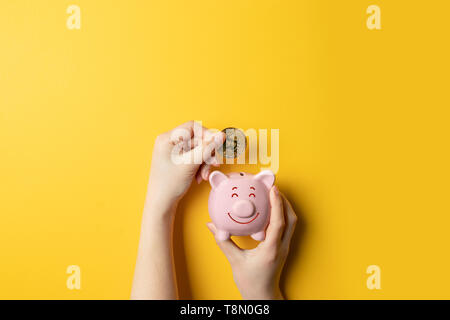 Weibliche Hände halten Piggy piggy Bank und bitcoin Geld in das Sparschwein. Stockfoto