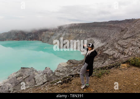 Frau touristische schaut den Schwefel See auf dem Ijen Vulkan auf der Insel Java in Indonesien. Wanderer weibliche Reisen auf Top Mountain - Konzept Stockfoto