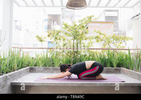 Asiatische Frau im Urlaub entspannen. Spielen, wenn Yoga. Auf dem Balkon Stockfoto