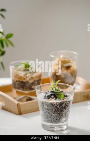 Obst Joghurt Parfait mit Müsli und Chia Samen für gesundes Frühstück auf hölzernen Tisch Stockfoto