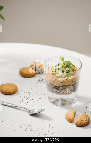 Bereit gesund Ein nahrhaftes Frühstück zu essen - Müsli mit Mandeln, Chia Samen, Banane und Kiwi Früchte und Beeren und ein Glas mit Milch in der Nähe Stockfoto