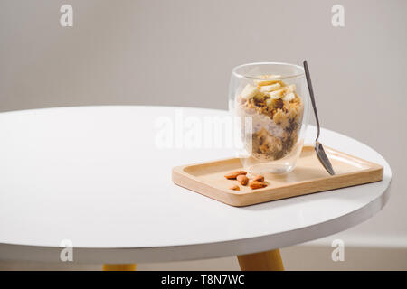 Bereit gesund Ein nahrhaftes Frühstück zu essen - Müsli mit Mandeln, Chia Samen, Banane und Kiwi Früchte und Beeren und ein Glas mit Milch in der Nähe Stockfoto