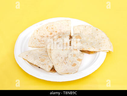 Weißbuch Platte mit Chicken Quesadilla, in Viertel schneiden auf gelb tischdecke. Beliebte Straße Messe Essen. Stockfoto