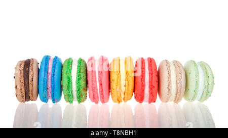 Reihe von Macaron Cookies Seitenlage nebeneinander mehrere Farben und Aromen auf einer reflektierenden Oberfläche isoliert auf Weiss. Traditionelle französische behandeln. Stockfoto
