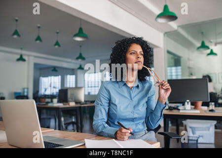 Junge Geschäftsfrau Ideen schreiben in ein Notebook am Schreibtisch Stockfoto