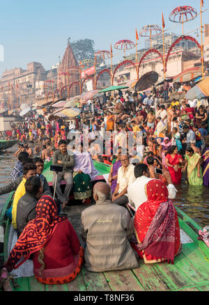 Touristen in einem Boot wath Anbeter darstellende rituelle Bad und Gebete in den Fluss Ganges, Varanasi, Indien Stockfoto