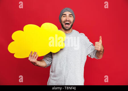 Bild von schöner Mann 30 s tragen Hut holding Nachricht Blase über den roten Hintergrund isoliert Stockfoto