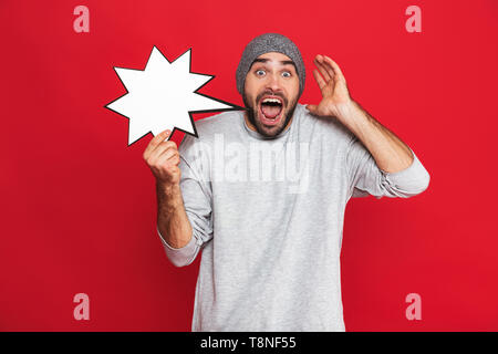 Bild Der unrasierte Mann 30 s tragen Hut Holding leere Idee Poster über den roten Hintergrund isoliert Stockfoto
