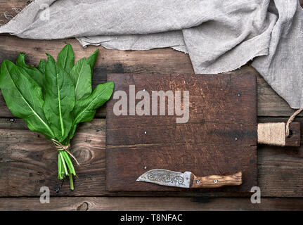 Bündel frische grüne Sauerklee Blätter und alte braune Schneidbrett auf einem Holztisch, Ansicht von oben Stockfoto