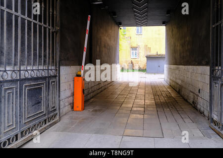 Eine dunkle Gasse, die mit einem massiven Tor. Automatische Schranke Stockfoto
