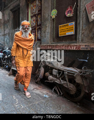 Hindu-priester Spaziergänge Pass eine verlassene Motorrad in den engen Gassen der Altstadt von Varanasi, Indien Stockfoto