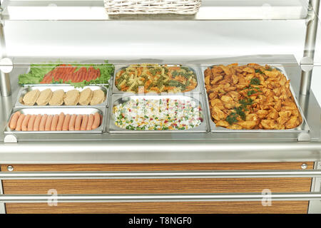 Schaufenster Kühlschrank für die Verpflegung mit warmen Speisen. Süße Desserts, warme Speisen und Salate. Stockfoto