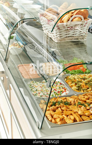 Schaufenster Kühlschrank für die Verpflegung mit warmen Speisen. Süße Desserts, warme Speisen und Salate. Stockfoto