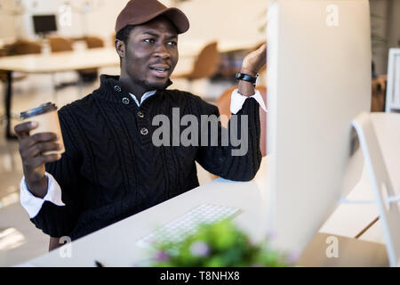 Schockiert afrikanischen Geschäftsmann in Anzug Gefühl durch on-line-Nachrichten am Bildschirm des Computers am Arbeitsplatz mit Laptop suchen betäubt, betonte Unternehmer investieren Stockfoto