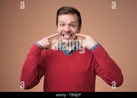 Junge europäische Mensch zeigt auf seine Zähne. Stockfoto