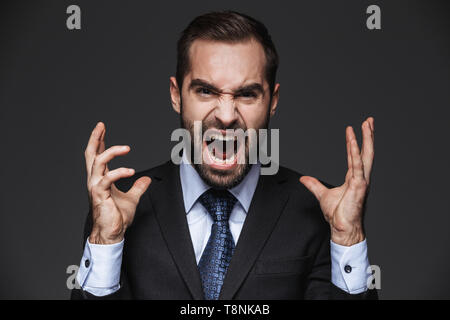 Porträt eines Verrückten gut aussehender Geschäftsmann tragen Klage über schwarzen Hintergrund isoliert, haben Kopfschmerzen Stockfoto