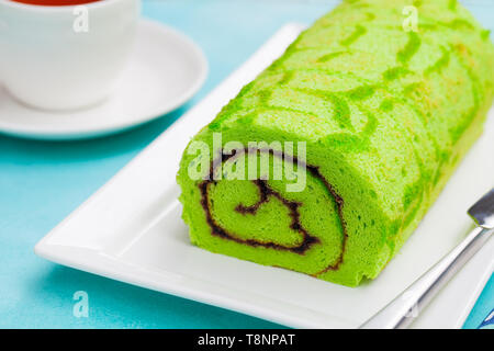 Grüne roll Kuchen mit einer Tasse Kaffee auf blauem Hintergrund. Close Up. Stockfoto