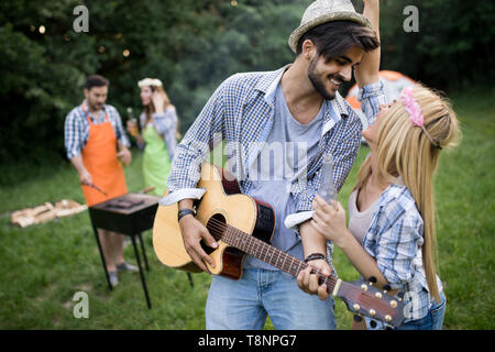 Junge Paare mit Freunden Lächeln und die gerösteten Barbecue im Campingplatz Stockfoto