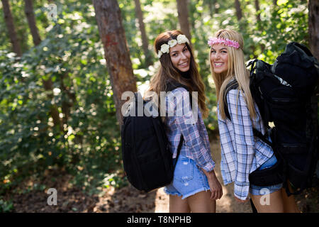 Abenteuer, Reisen, Tourismus, Wandern und Menschen Konzept. Gerne Frauen mit Rucksäcken im Wald Stockfoto