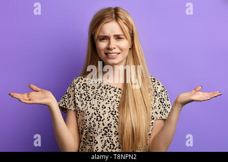 Unglücklich, traurig, wütend, verwirrt junge Mädchen in der Bluse zuckt die Schultern, die Arme, isolierte blauen Hintergrund. Bis schließen Foto Stockfoto