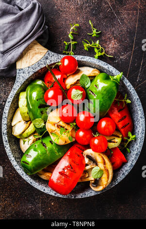 Gegrilltes Gemüse (Paprika, Zucchini, Champignons und Tomaten in einer Pfanne, Ansicht von oben. Gesunde vegane Ernährung Konzept. Stockfoto